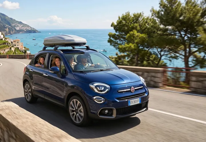 Una famiglia sorridente in auto su una strada lungo il mare
